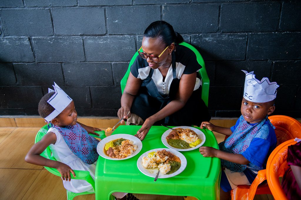 A caregiver serving lunch to children at the Feed My Sheep center