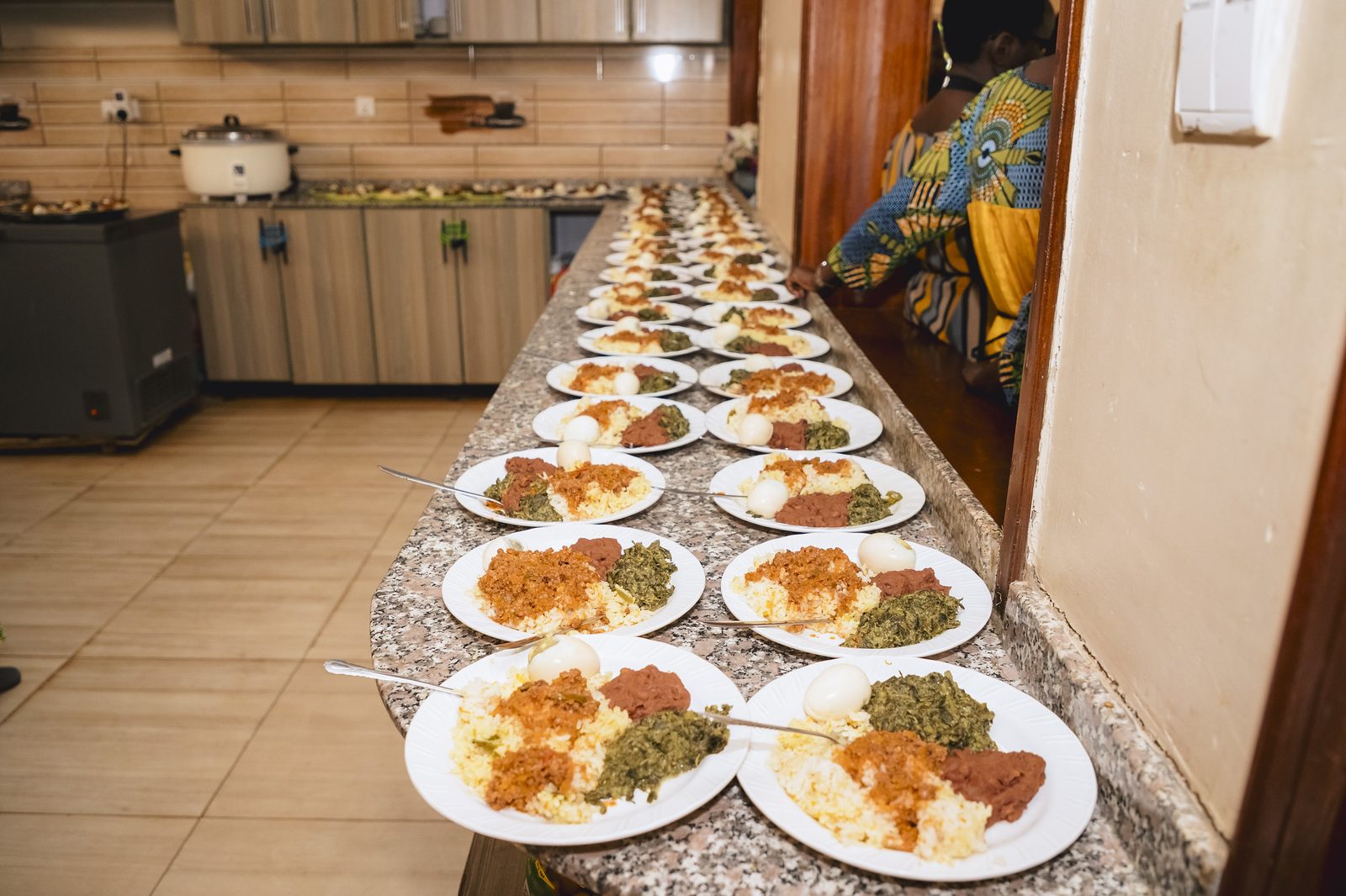 A long line of plated meals on the kitchen counter, ready for distribution